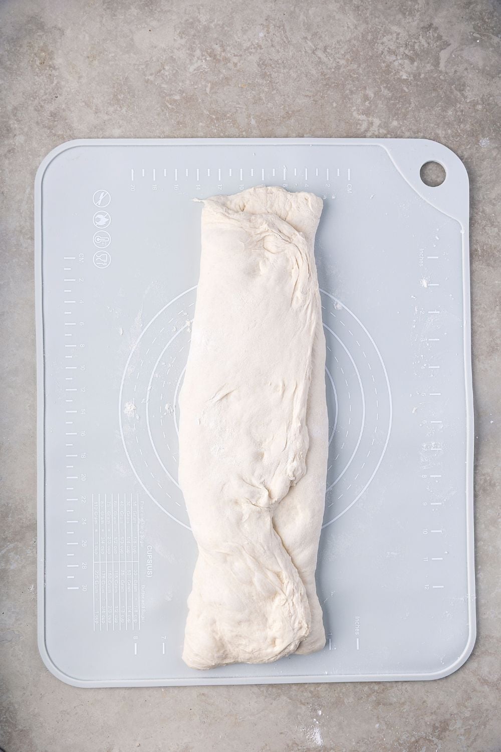 Homemade Sourdough Bread dough folded up on a cutting board on table 