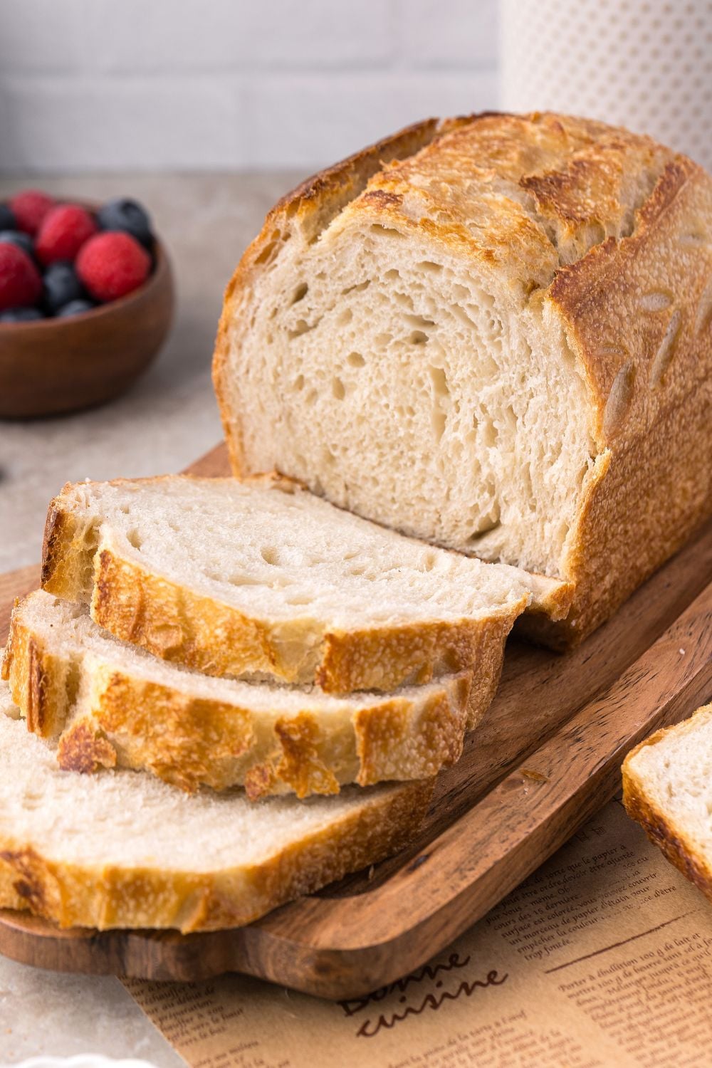 Homemade Sourdough Bread on a tray on table with some of the bread sliced to show the texture 