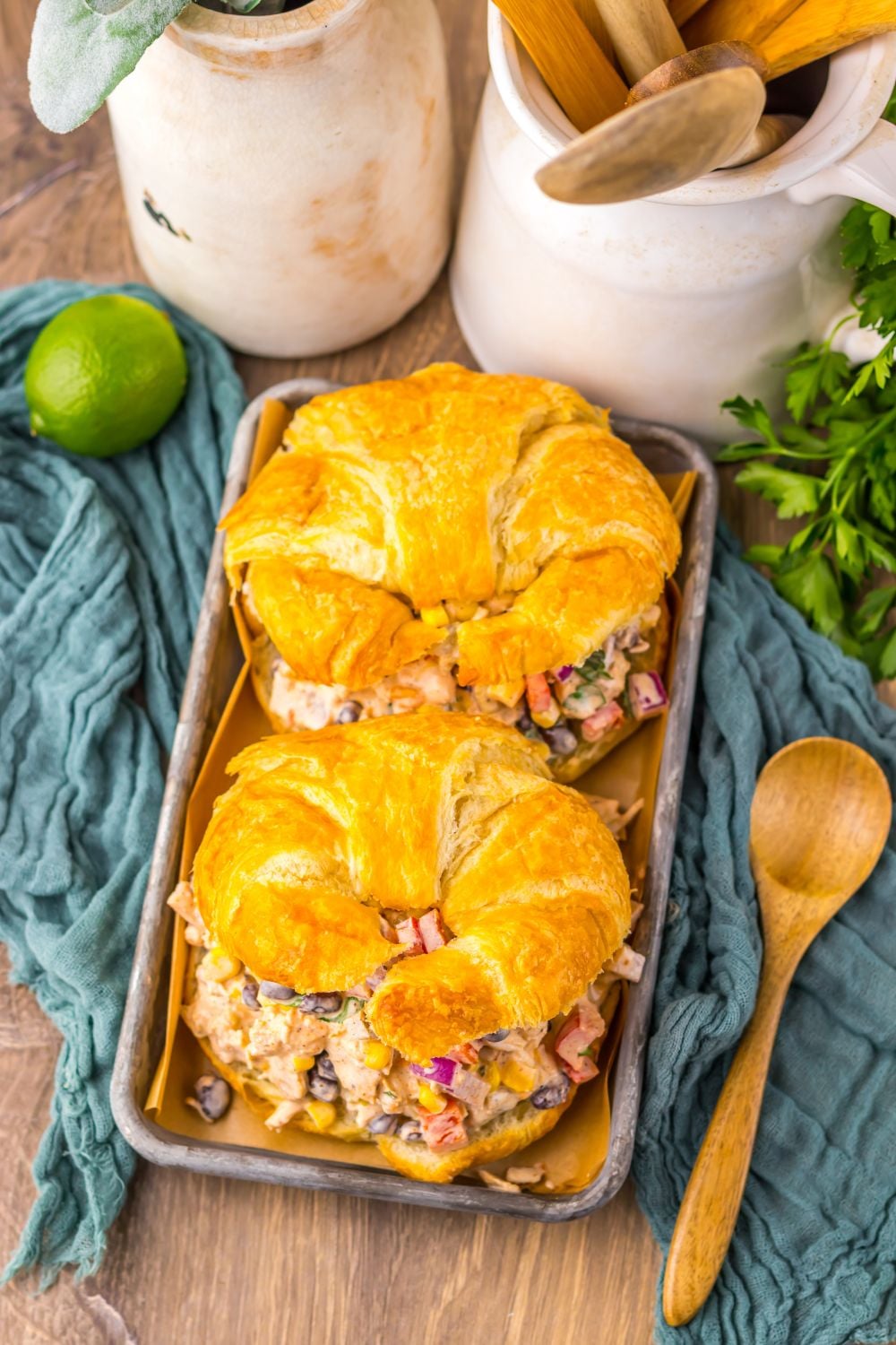 overhead look of table with Creamy Taco Chicken Salad sandwiches on table with lime and cilantro to side