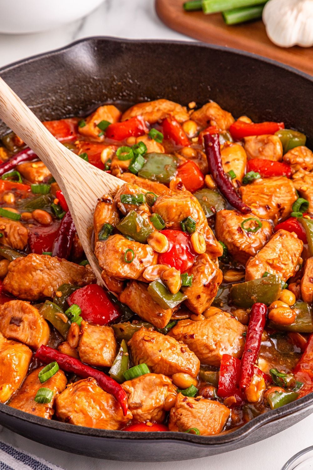 Better Than Takeout Kung Pao Chicken in a skillet with a spoon scooping up some of the meat