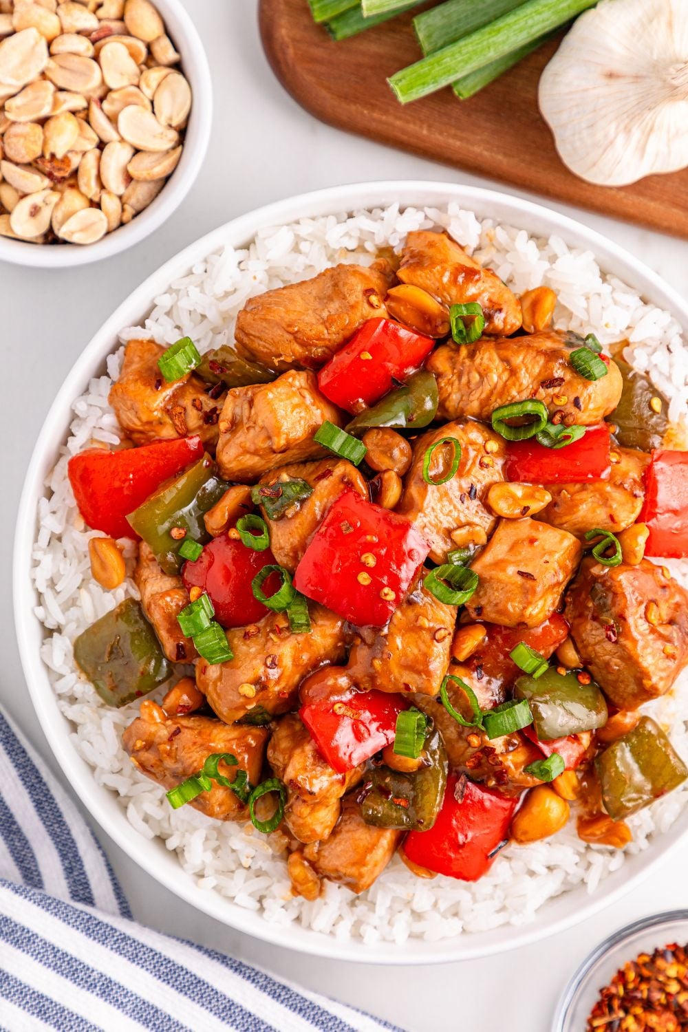Better Than Takeout Kung Pao Chicken on a plate with rice and ingredients in small bowls