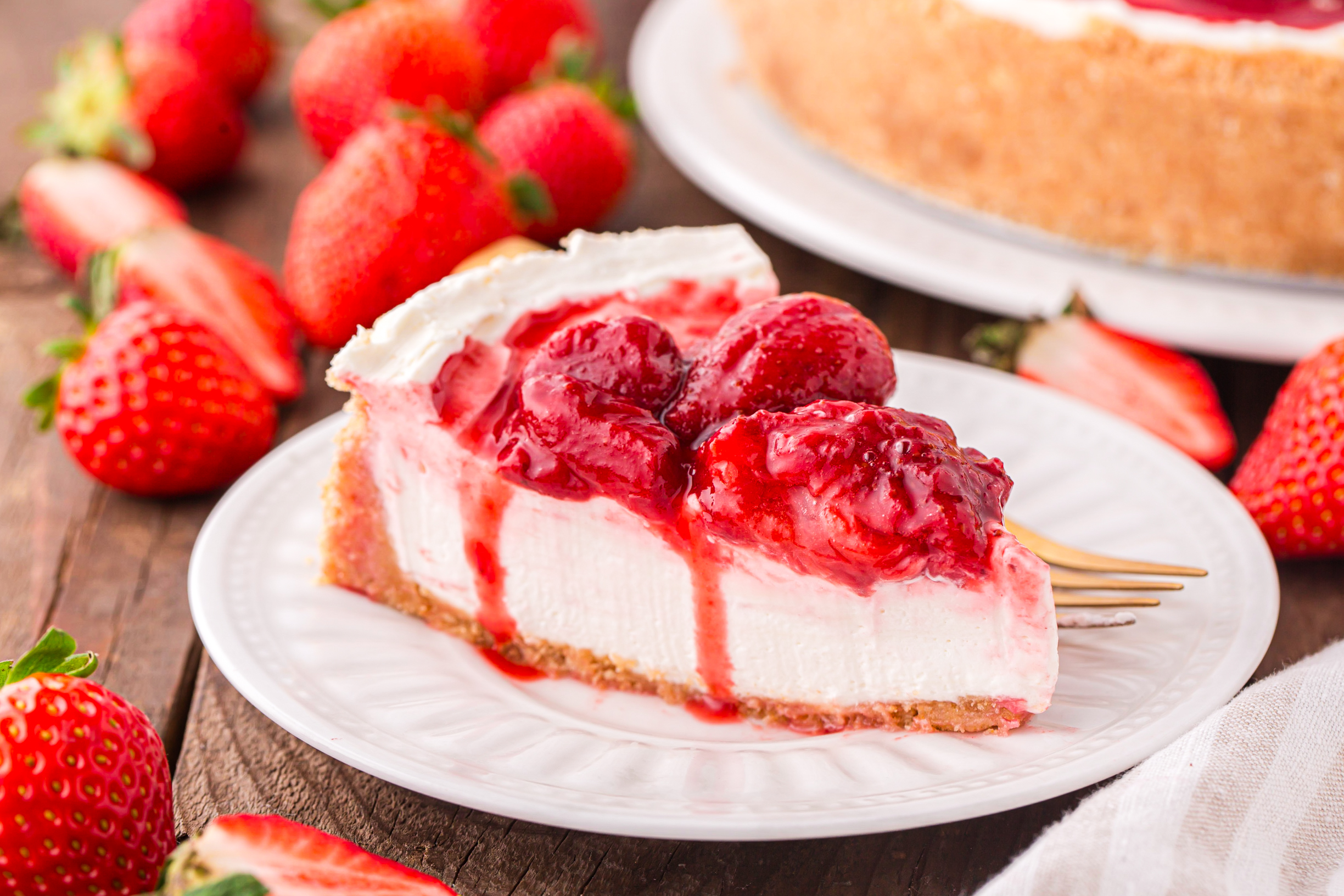 No Bake Strawberry Cheesecake from the side , on a white plate topped with strawberries