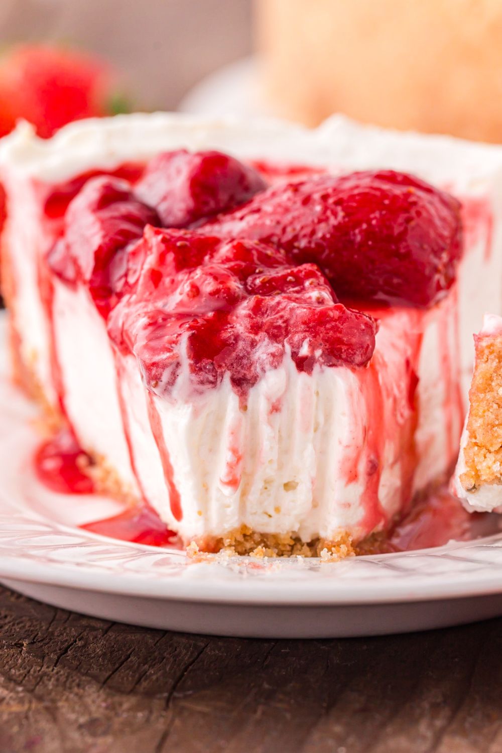 a single slice of No Bake Strawberry Cheesecake on a plate with a bite taken out of it