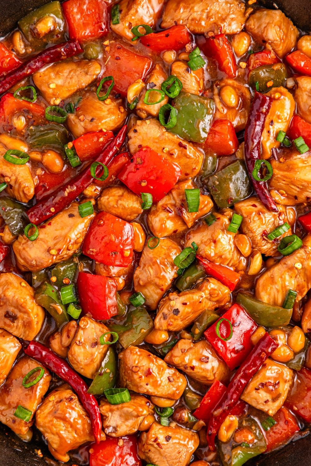 Better Than Takeout Kung Pao Chicken in a pan with close up so you can see the meat and veggies coated in sauce