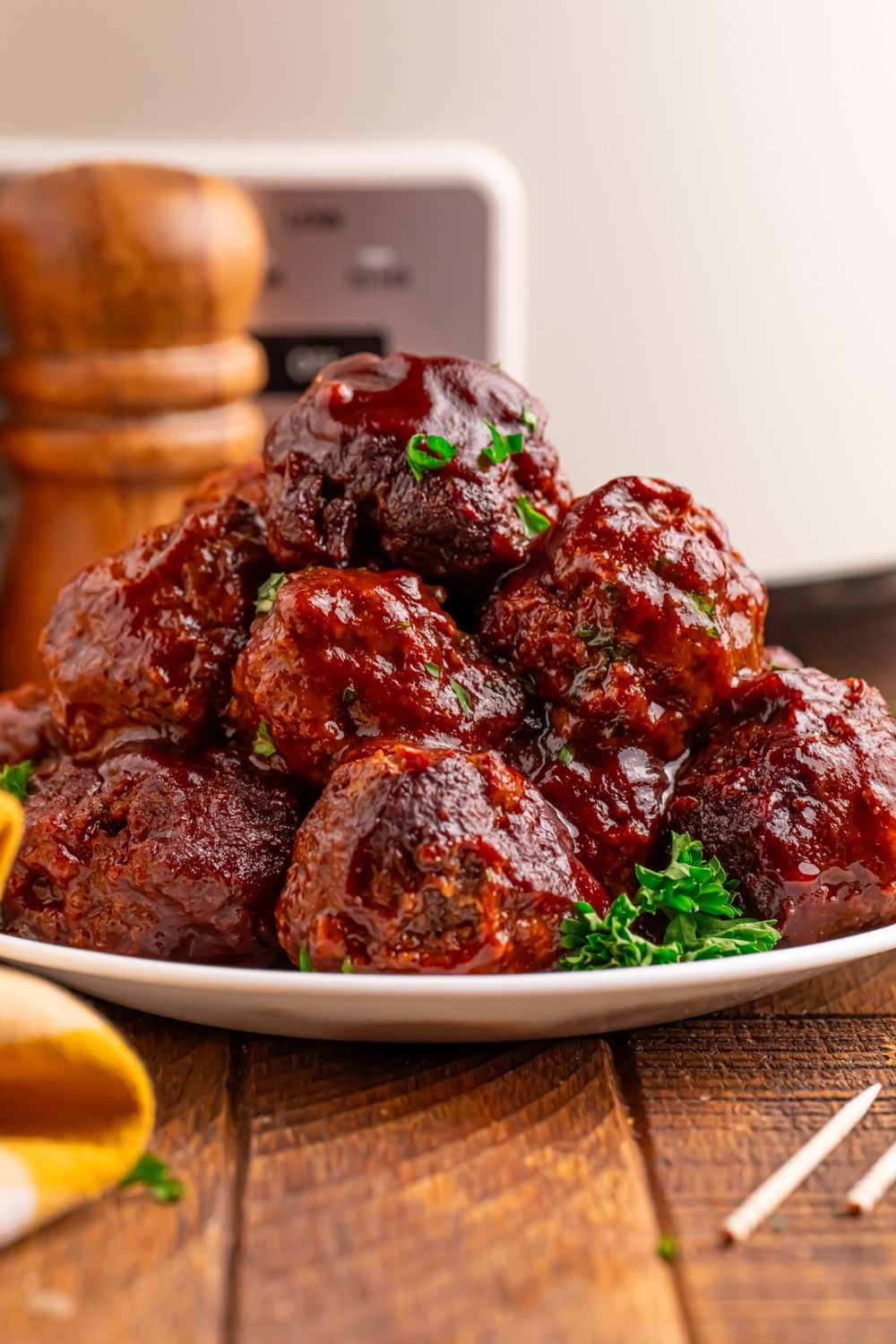 Crockpot Homemade BBQ Meatballs stacked on table with parsley on side and toothpicks to side
