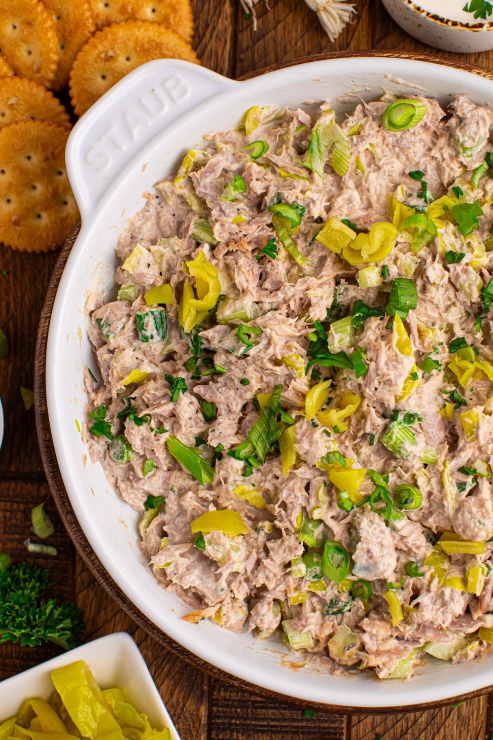Pepperoncini Ranch Tuna Salad in a white bowl on table with crackers and more peppers in a bowl to the side on table 