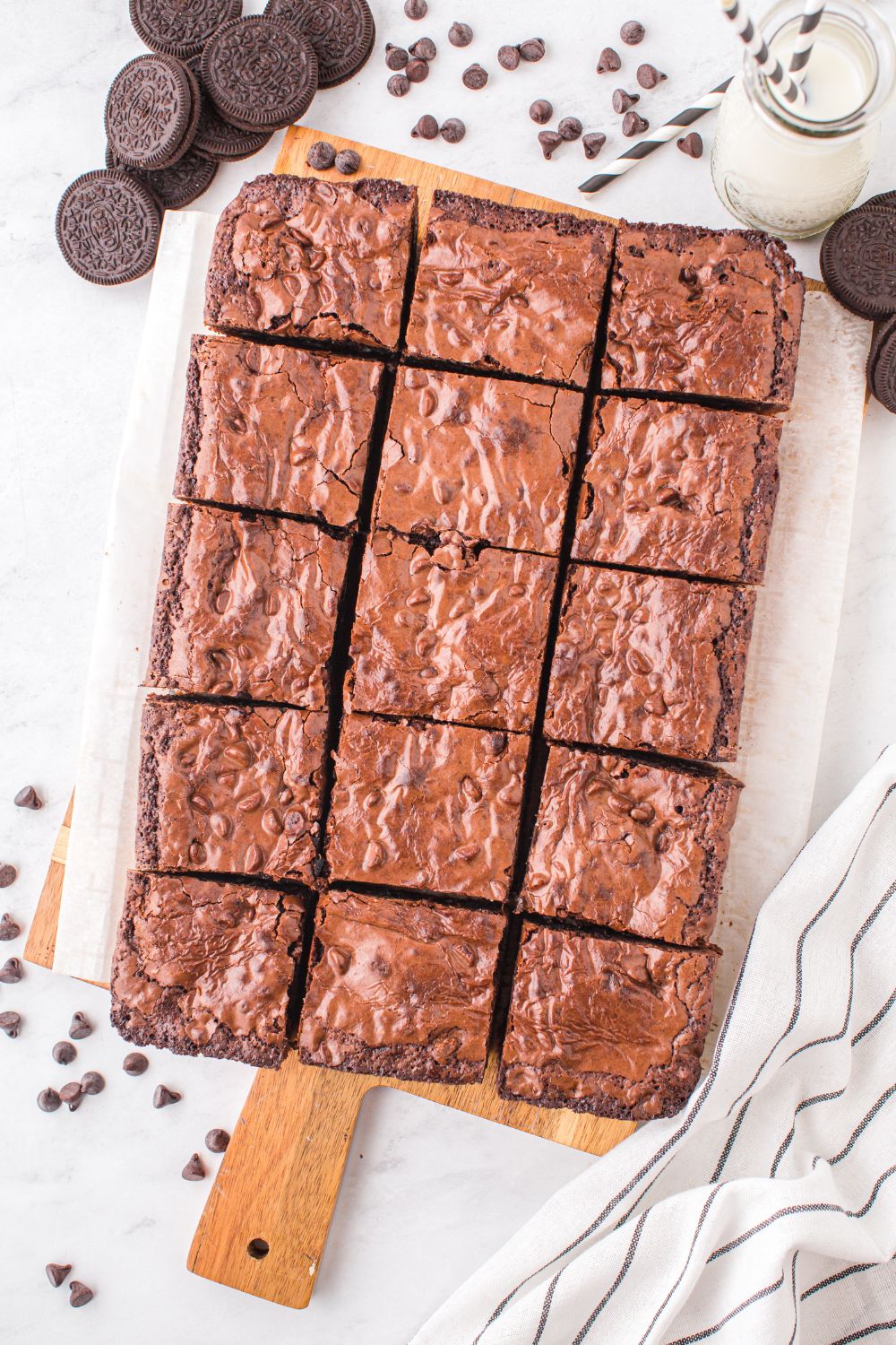 Slutty Brownies sliced and placed on a tray on table with chocolate chips and cookies 