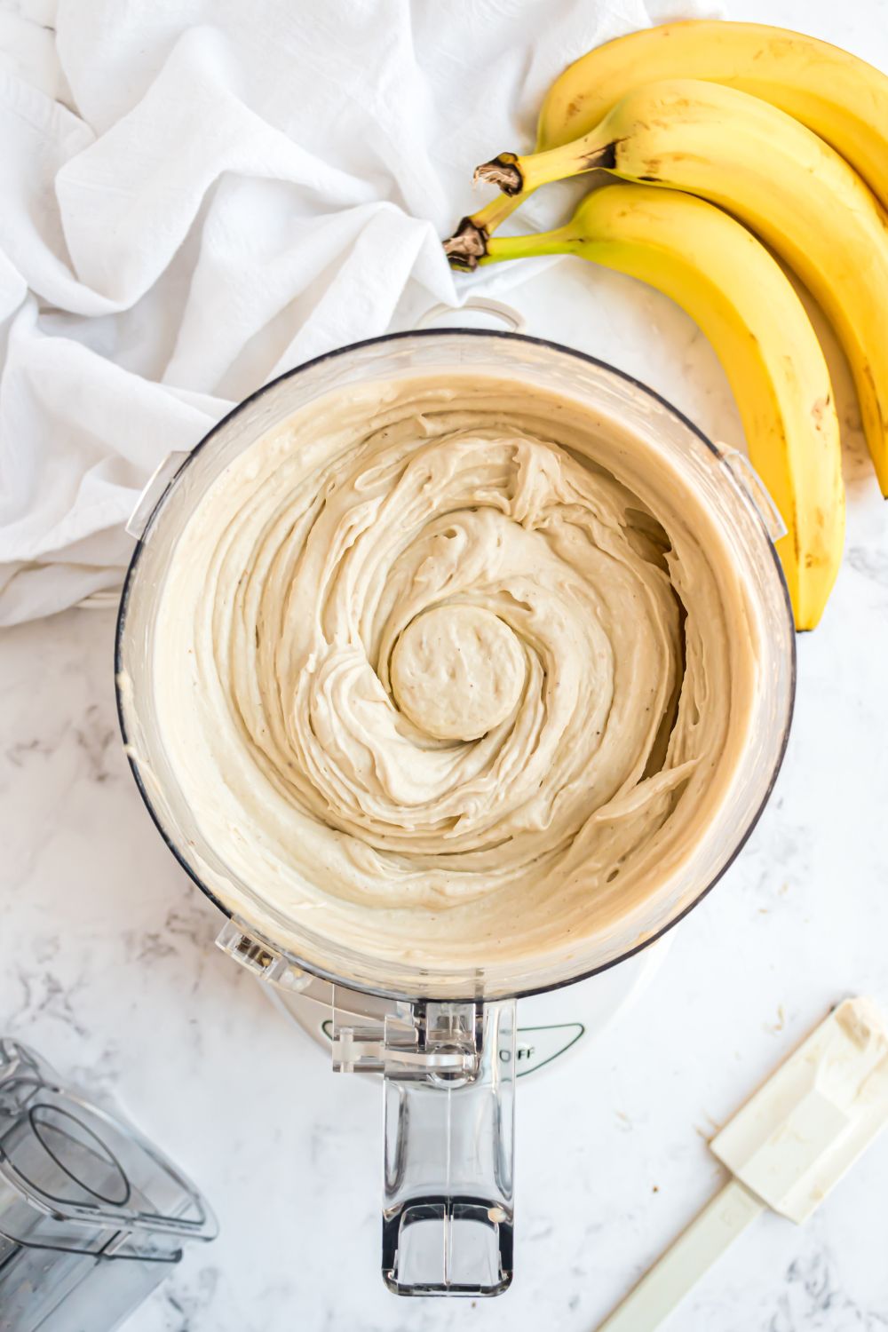 Banana Ice Cream in a food processor all mixed up with bananas to side 