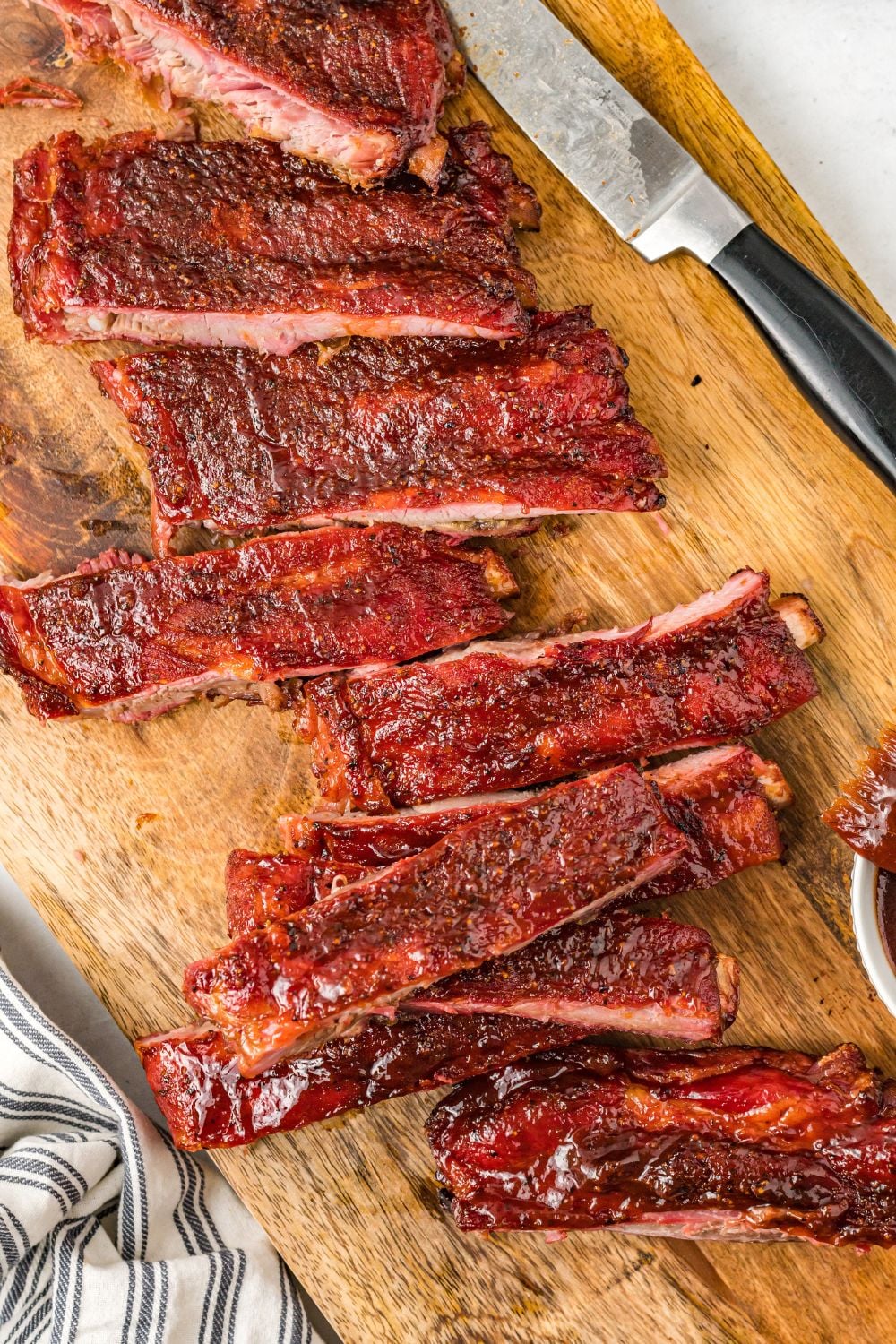 looking down at table with Grilled BBQ Baby Back Ribs cut into strips with a knfe to side
