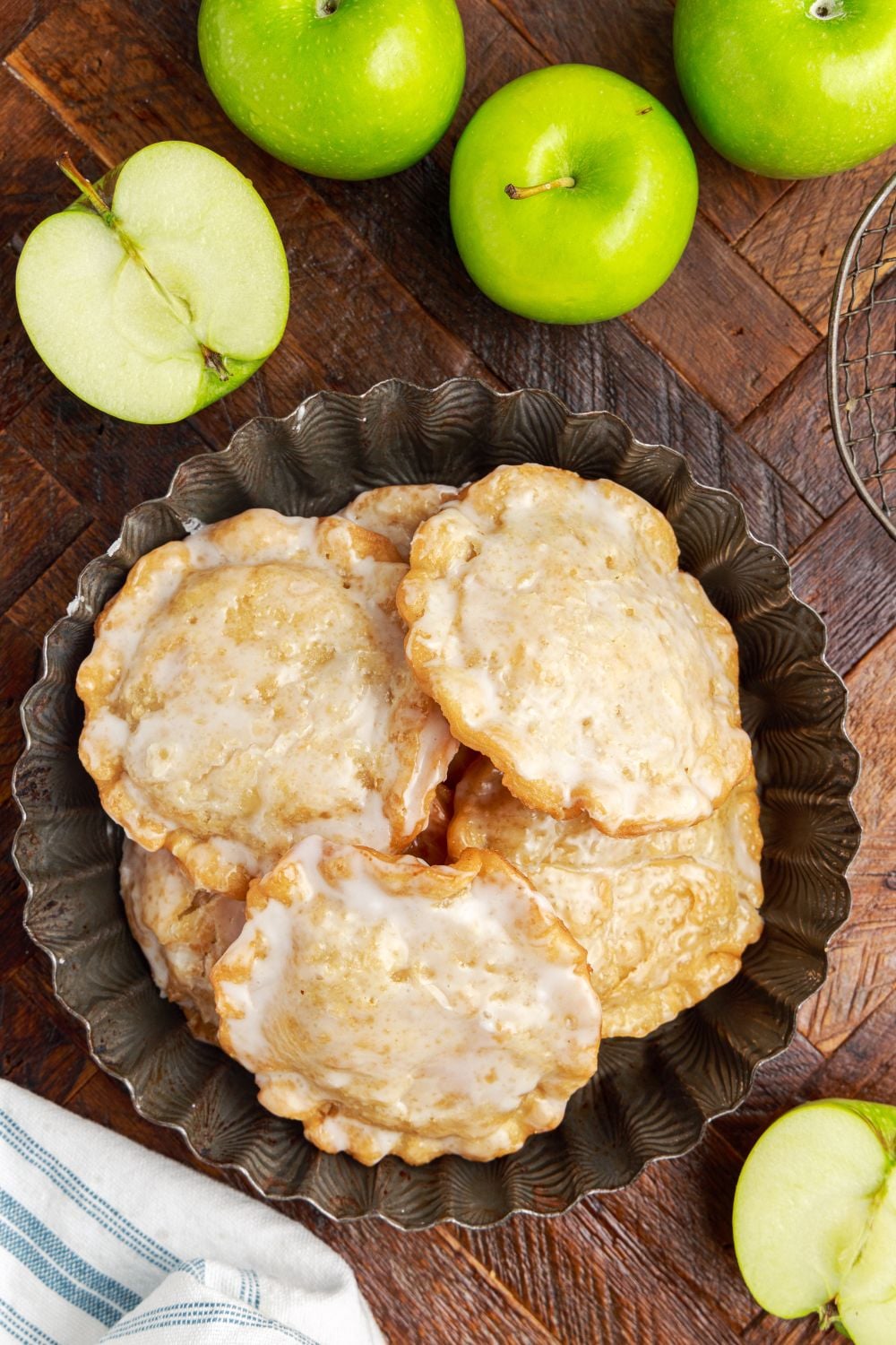 Deep Fried Apple Hand Pies on a plate with a bunch of apples around it on table and one apple cut in half