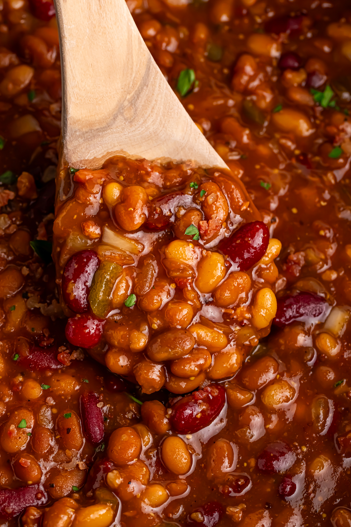 Crockpot bourbon baked beans in a bowl with a spoon scooping some out