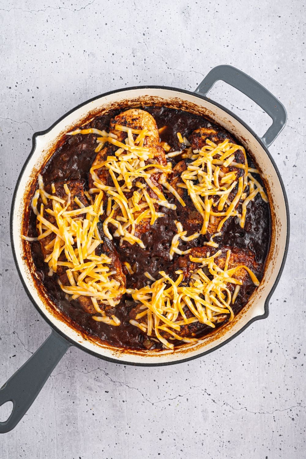 saucy Cheesy Salsa Chicken in a skillet with cheese sprinkled on top 
