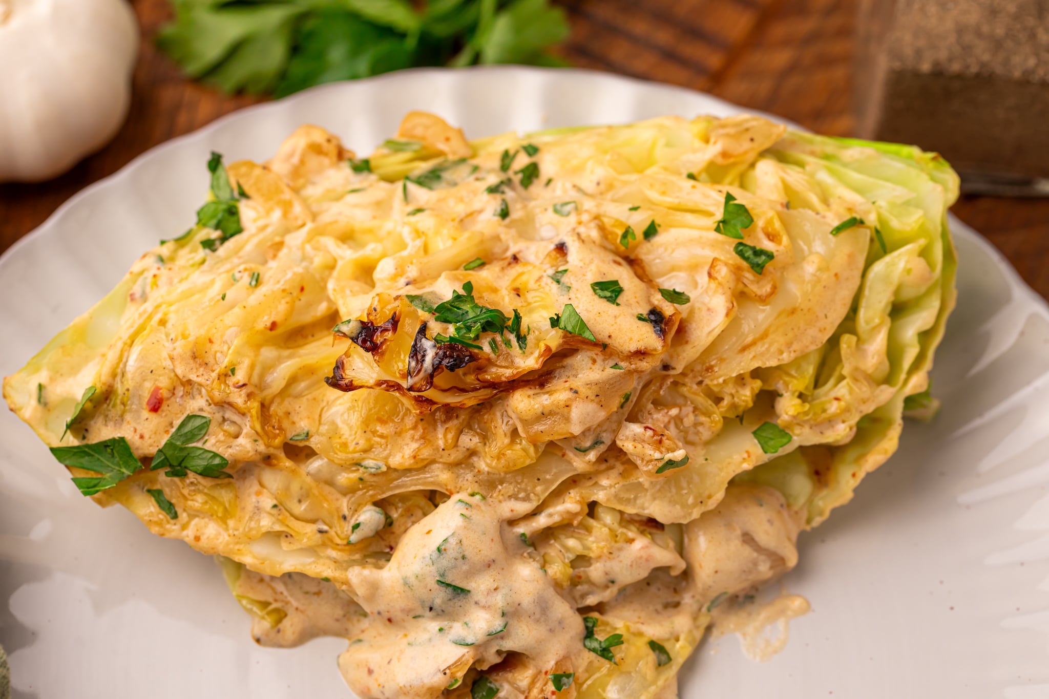 Creamy Garlic Parmesan Cabbage wedge on a white plate up close to show texture 