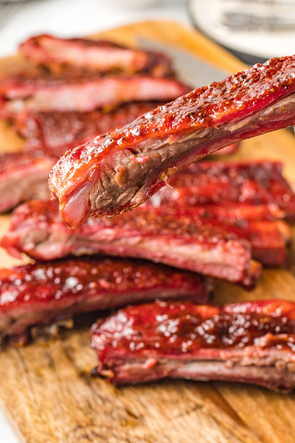 Grilled BBQ Baby Back Ribs on cutting board with one being held