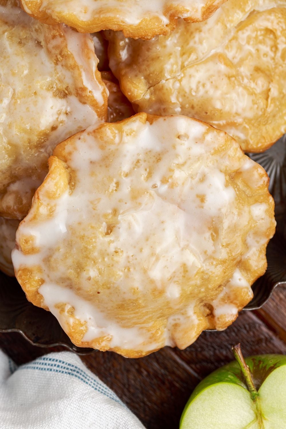 Deep Fried Apple Hand Pies spread out on table with a half an apple to the side