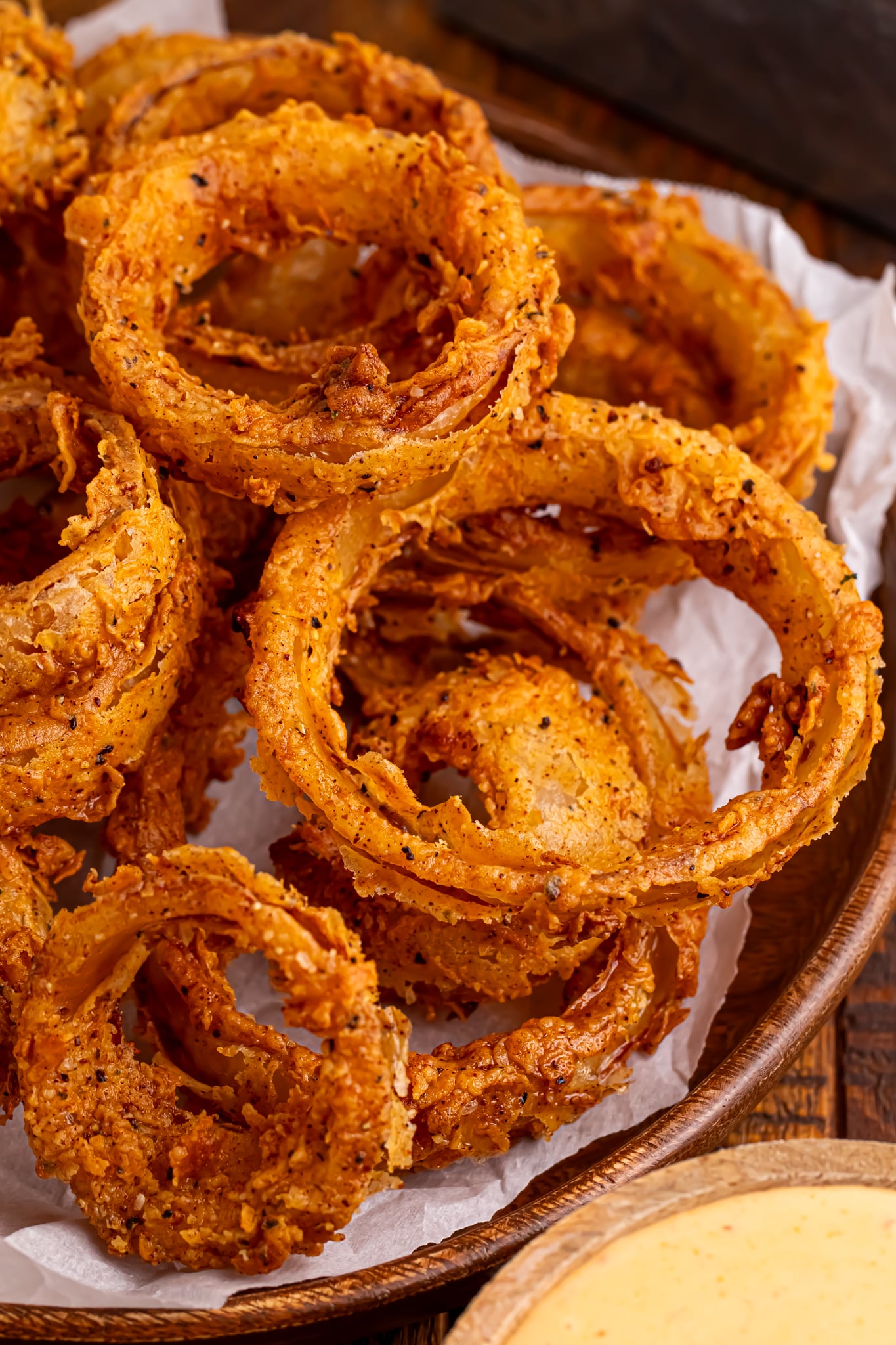Homemade Deep Fried Onion Rings stacked on tray with parchment paper under the tray