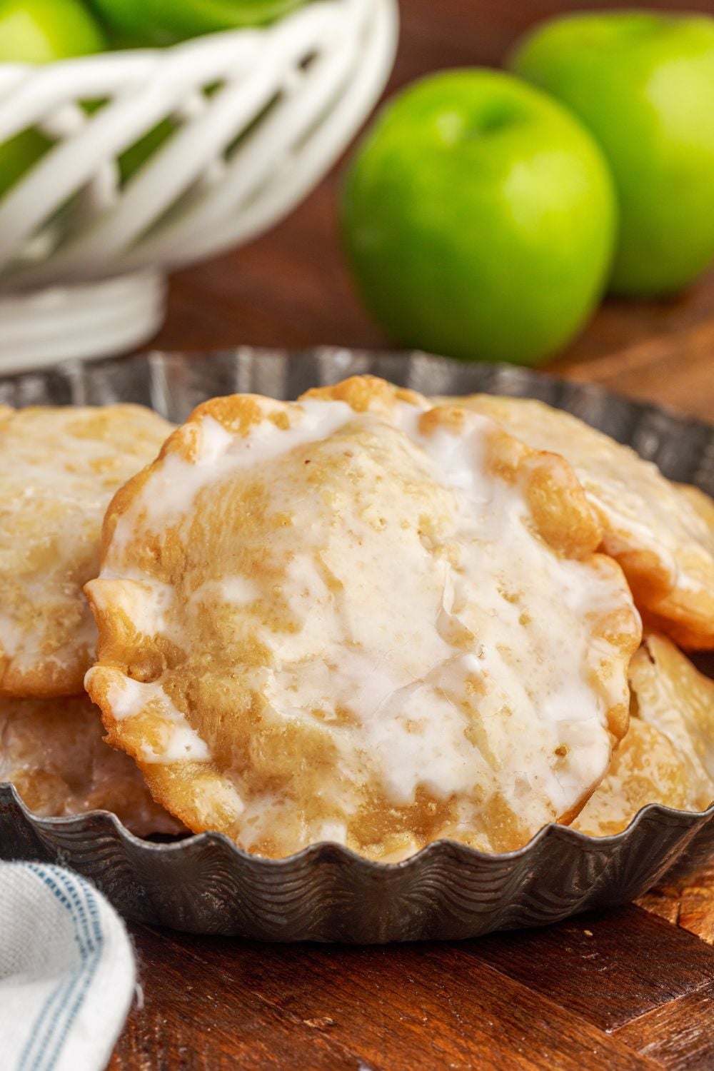Deep Fried Apple Hand Pies piled on a plate with green apples in background