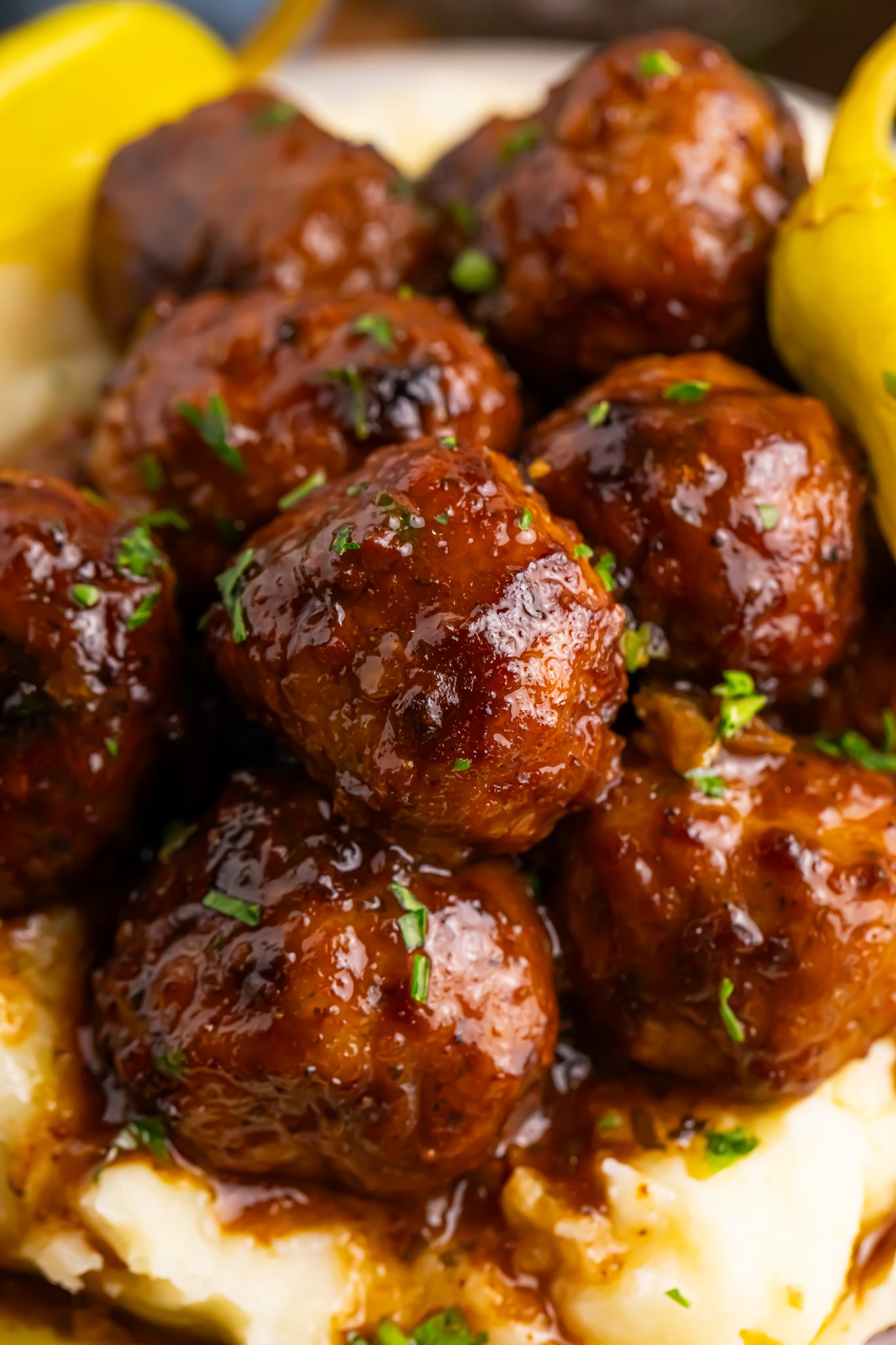 Crockpot Mississippi Meatballs on a plate with mashed potatoes underneath a fork to the side on table