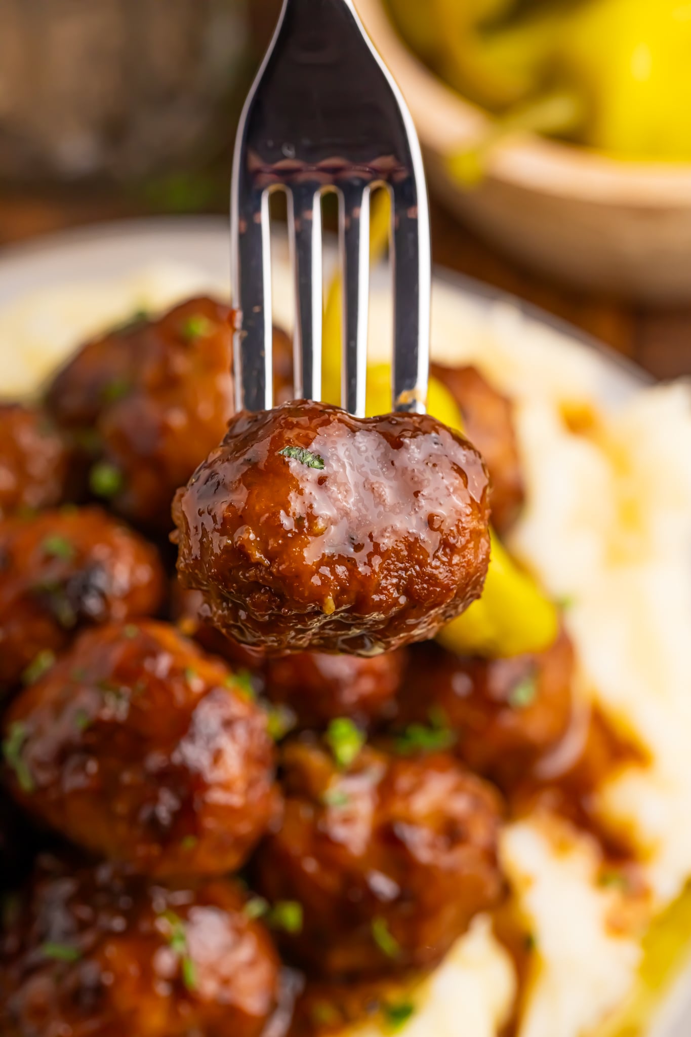 mashed potatoes and Crockpot Mississippi Meatballs on a plate and a fork with one meatball poked into it