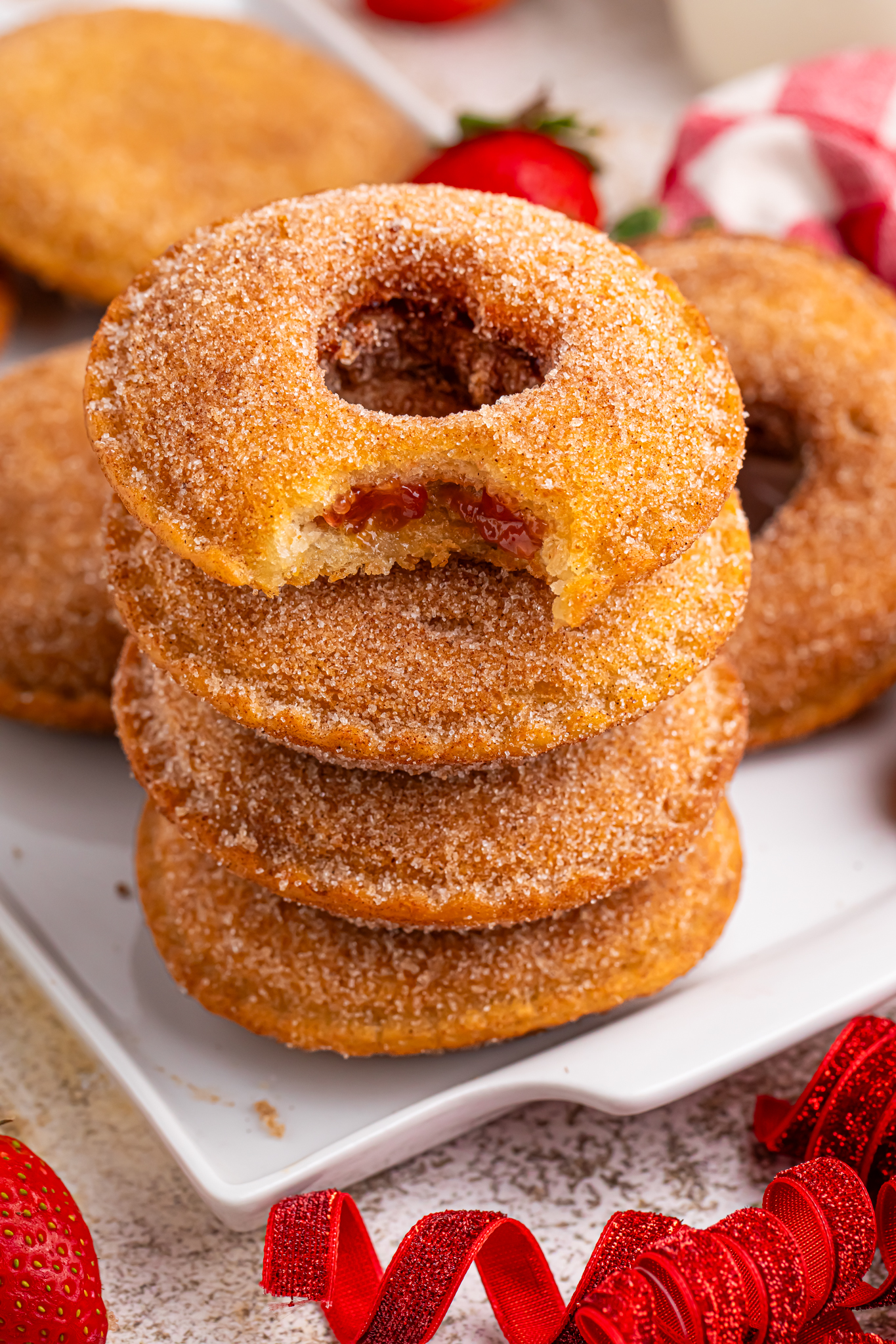 plate with Fried Strawberry Uncrustables that have been fried and rolled in sugar on plate with strawberries in front of plate 