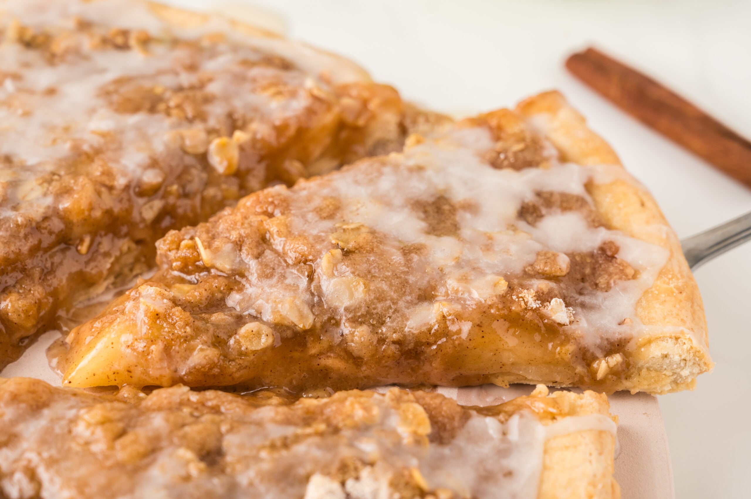close up of Apple Pie Pizza on a white table drizzled with icing
