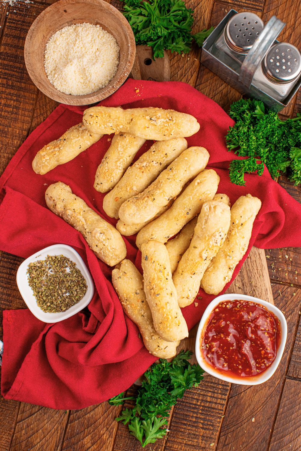 overhead look of breadstick with sauce, parmesan cheese, oregano and more