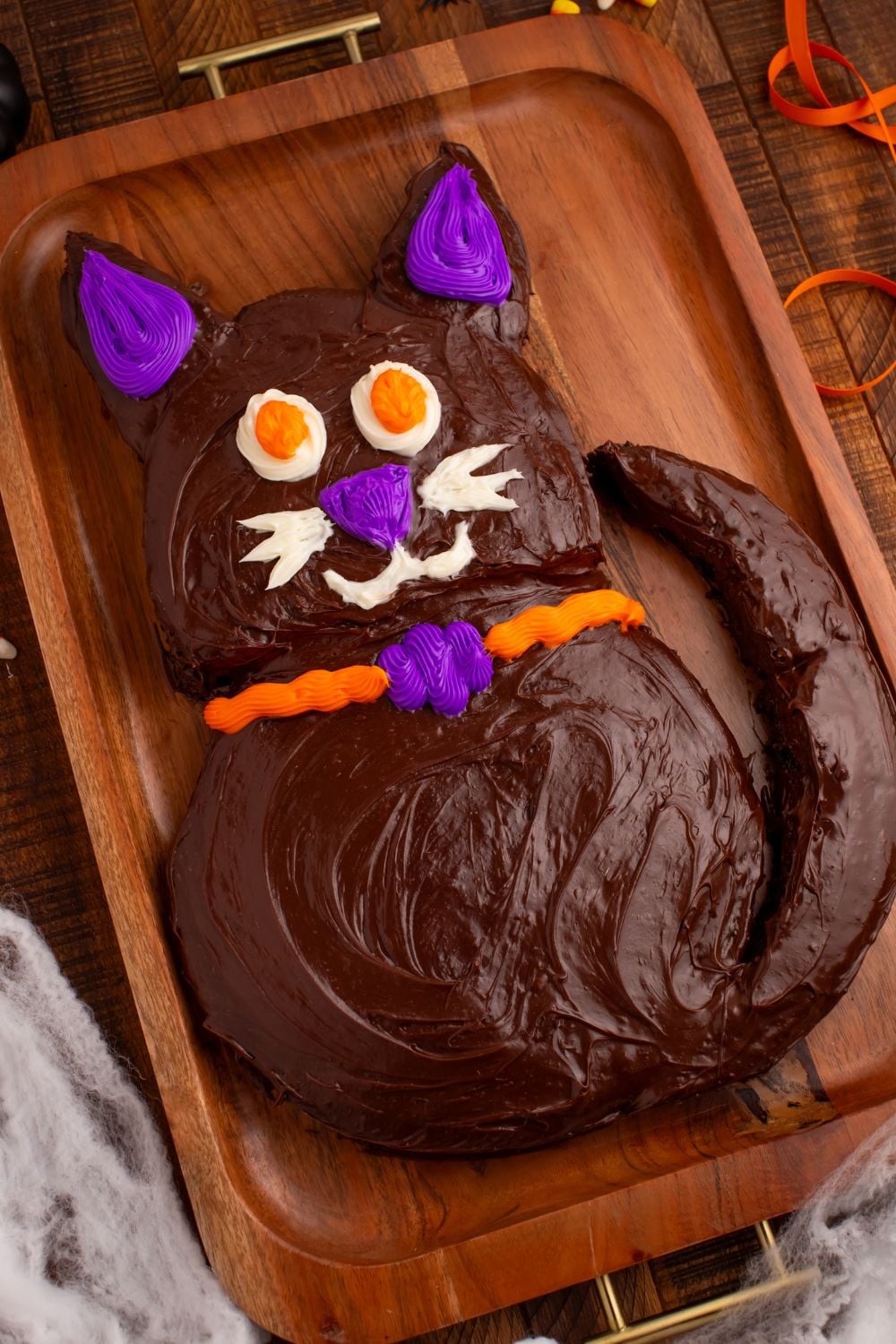Easy Halloween Black Cat Cut Out Cake on a serving tray with fake spider webs around bottom of tray 