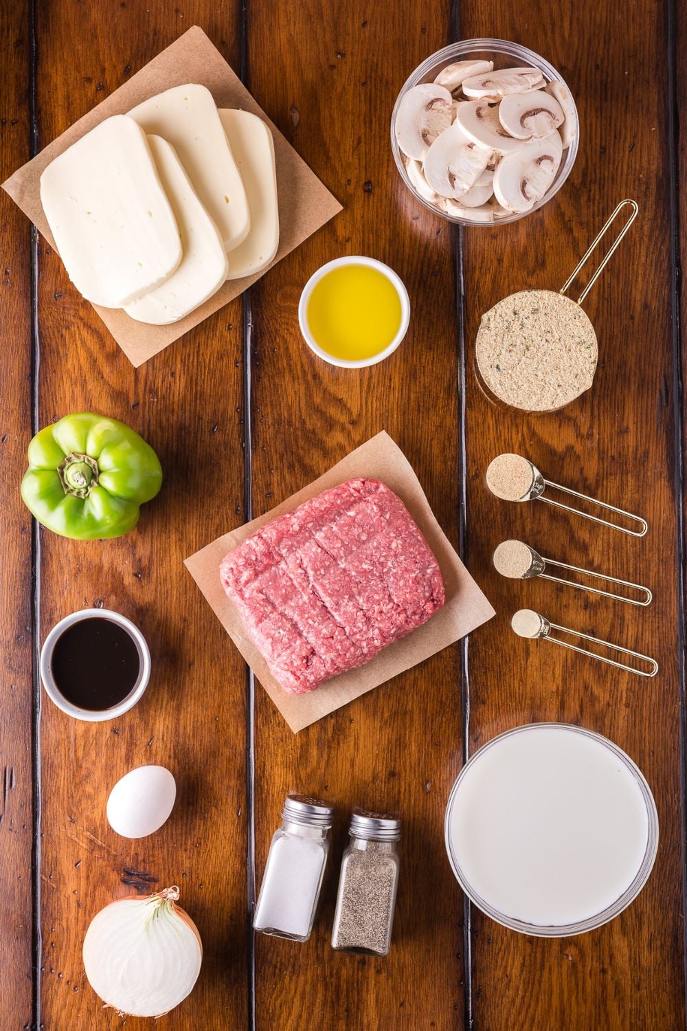 a wooden table topped with all the ingredients in single serve containers to make Stuffed Philly Cheesesteak Meatloaf