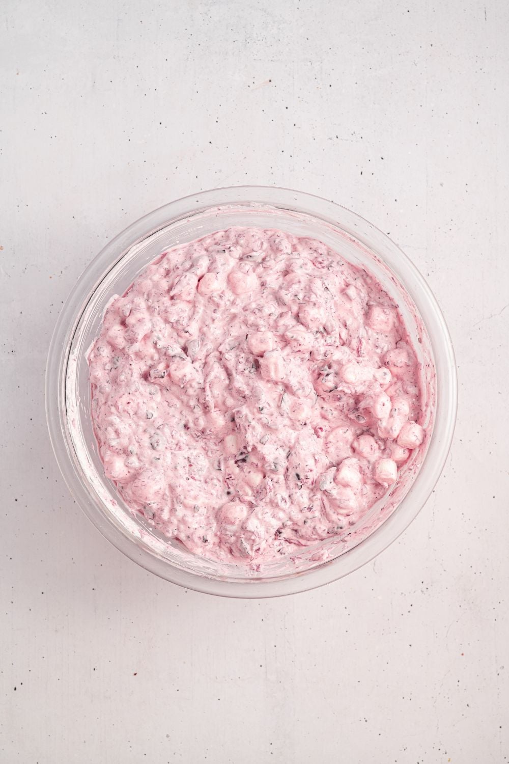 white counter with glass bowl full of Cranberry Fluff Salad mixed up