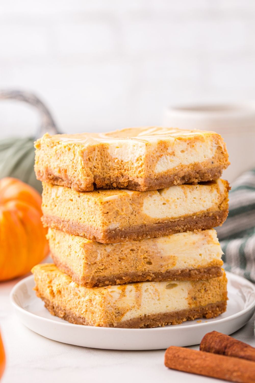 stack of Swirled Pumpkin Cheesecake Bars on plate and a bite taken out of it