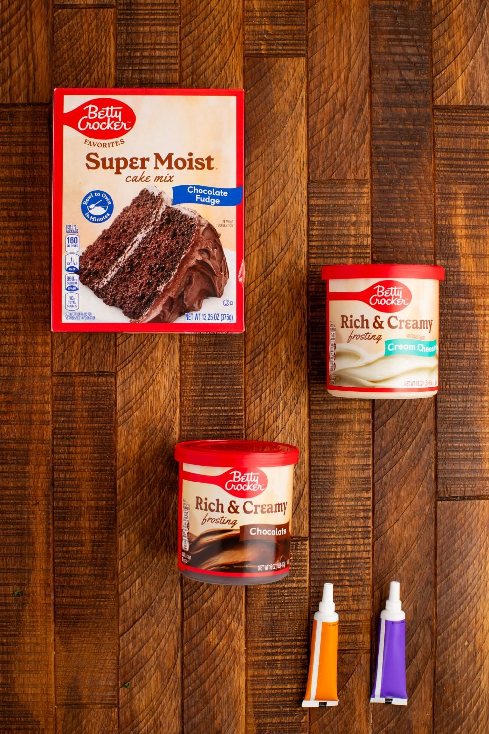 ingredients for making Easy Halloween Black Cat Cut Out Cake in containers sitting on the wooden table 