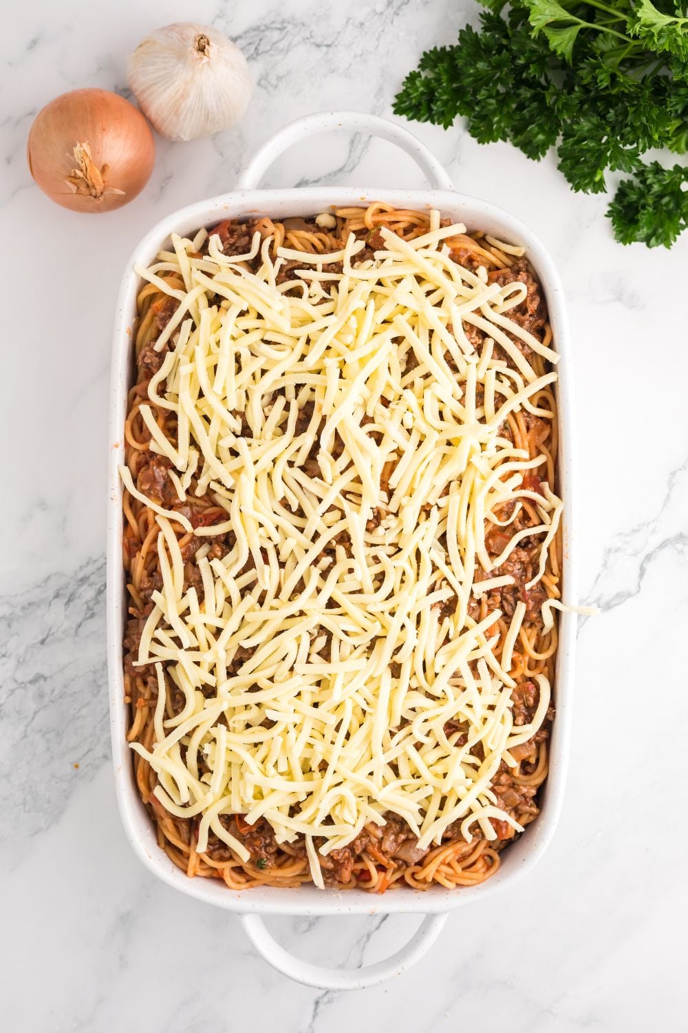 raw Million Dollar Spaghetti Casserole in a casserole pan on table waiting to be baked