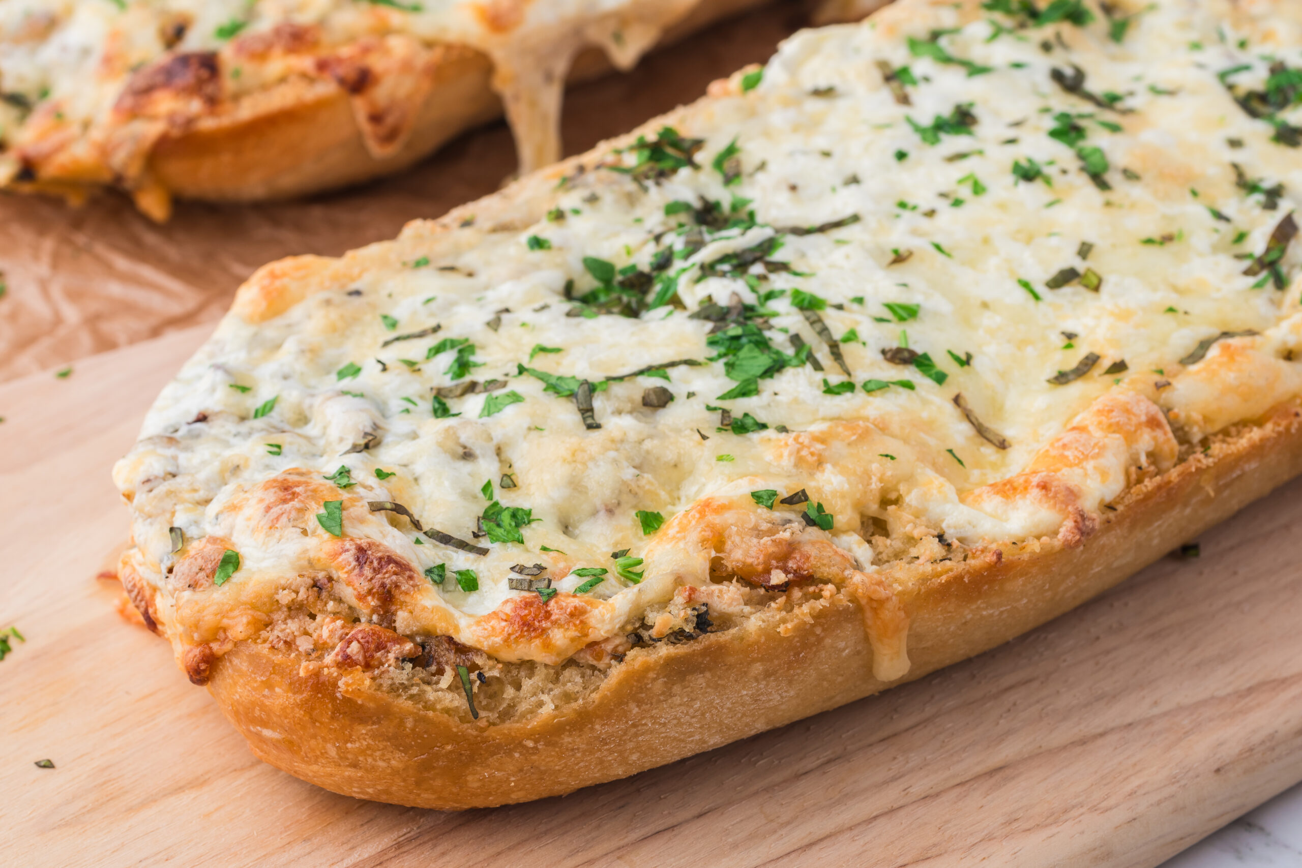 a cutting board with a loaf of the Cheesy Garlic Bread on it