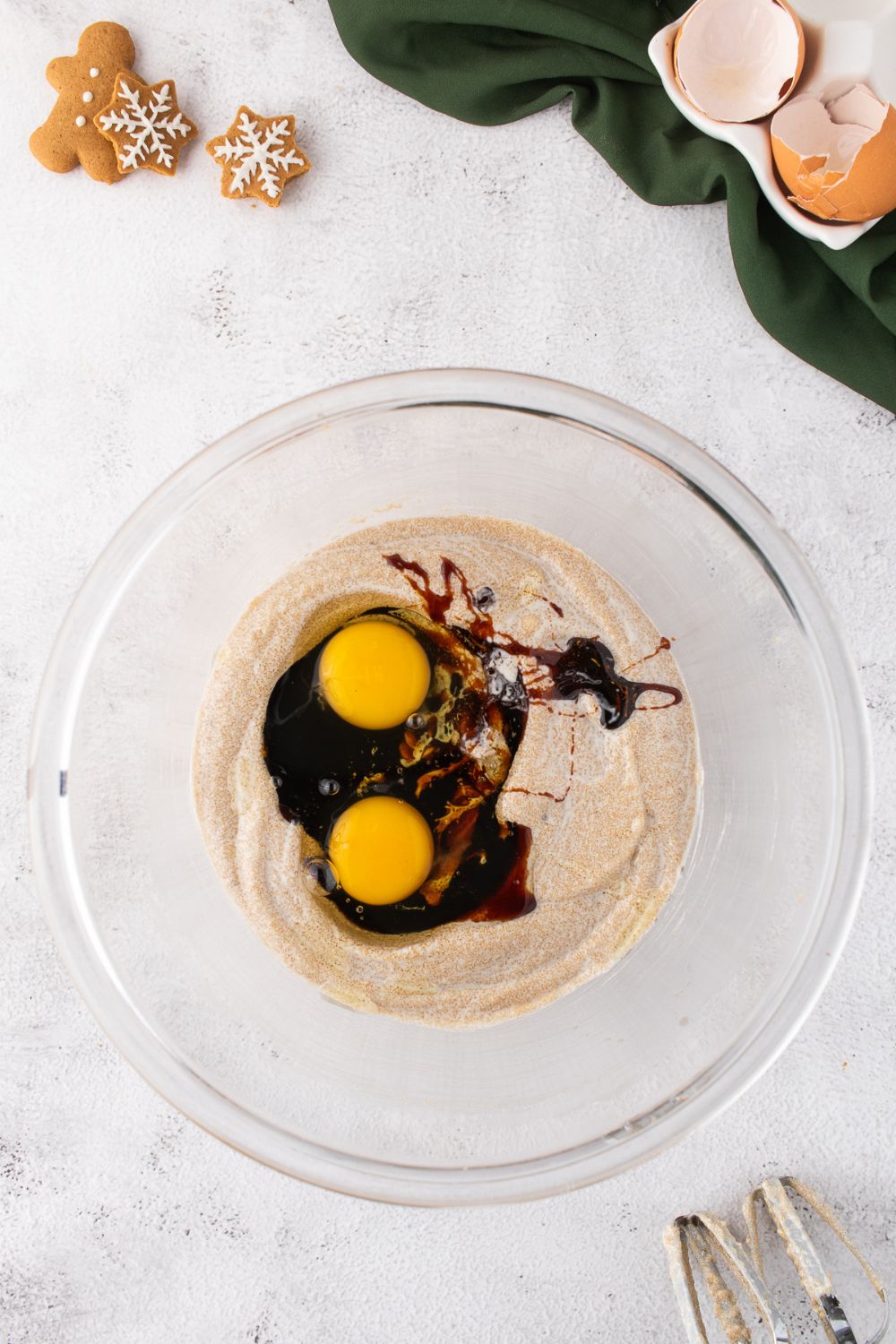 glass bowl of cake batter being mixed with some eggs and molasses on top