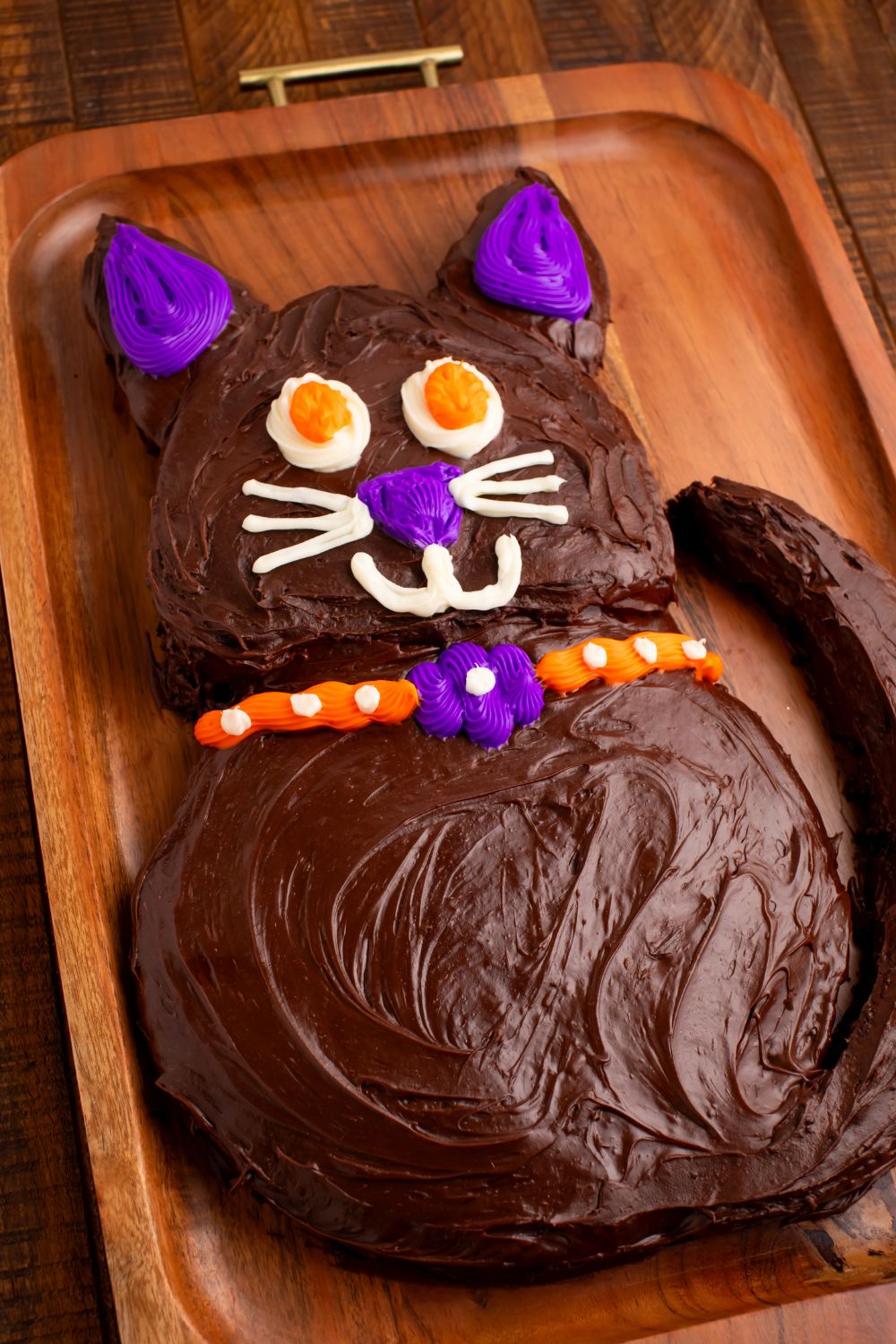 Homemade Halloween cake in the shape of a cat sitting on cutting board