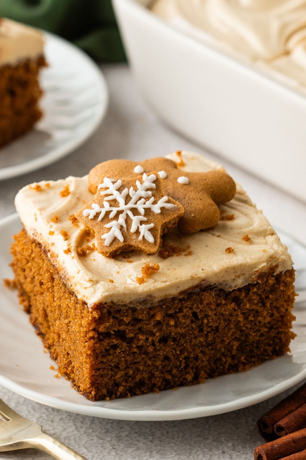 slices of Gingerbread Cake with Cream Cheese Frosting on plates sitting on table with main cake in pan