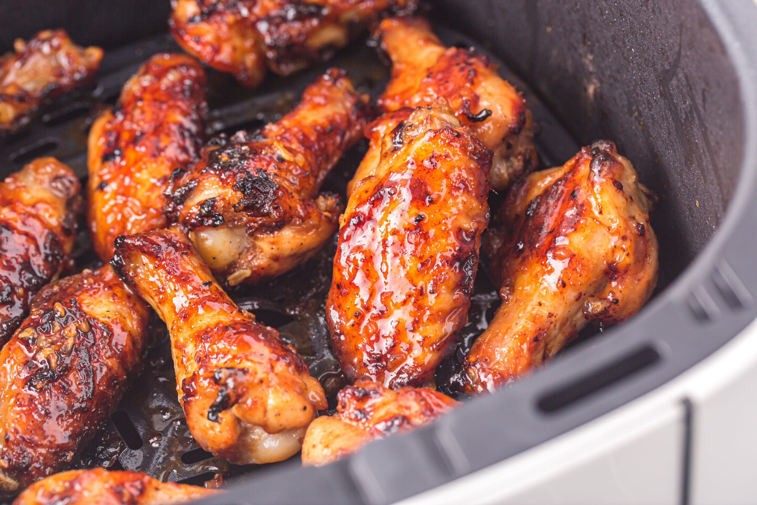 an Air Fryer Basket with the cooked Air Fryer Honey Garlic Chicken Wings inside