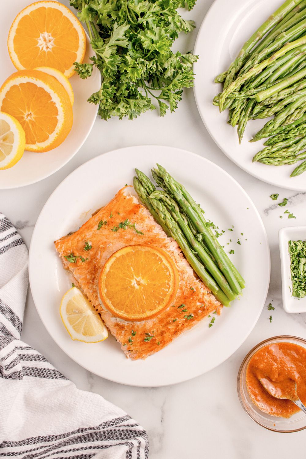 overhead look of table with Grilled Honey Mustard Salmon on plate, asparagus, sliced orange, and more