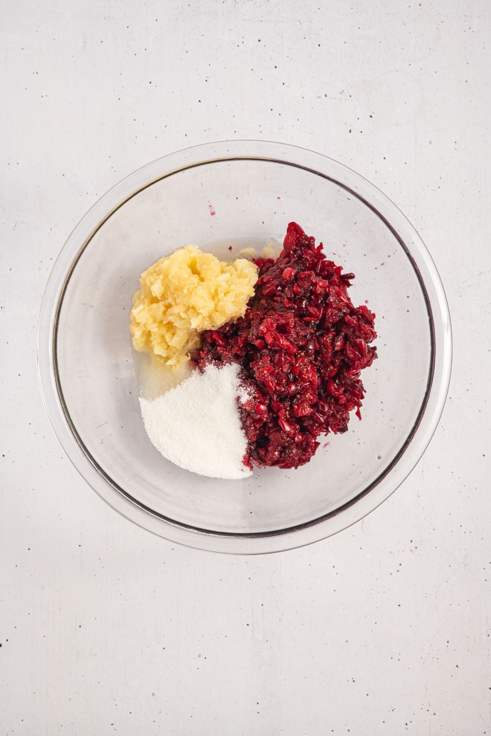 crushed cranberry mixture, sugar, and crushed pineapple in a glass bowl