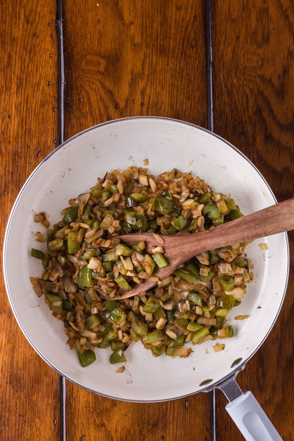 sauted onions and peppers cooked in a skillet on a wooden table