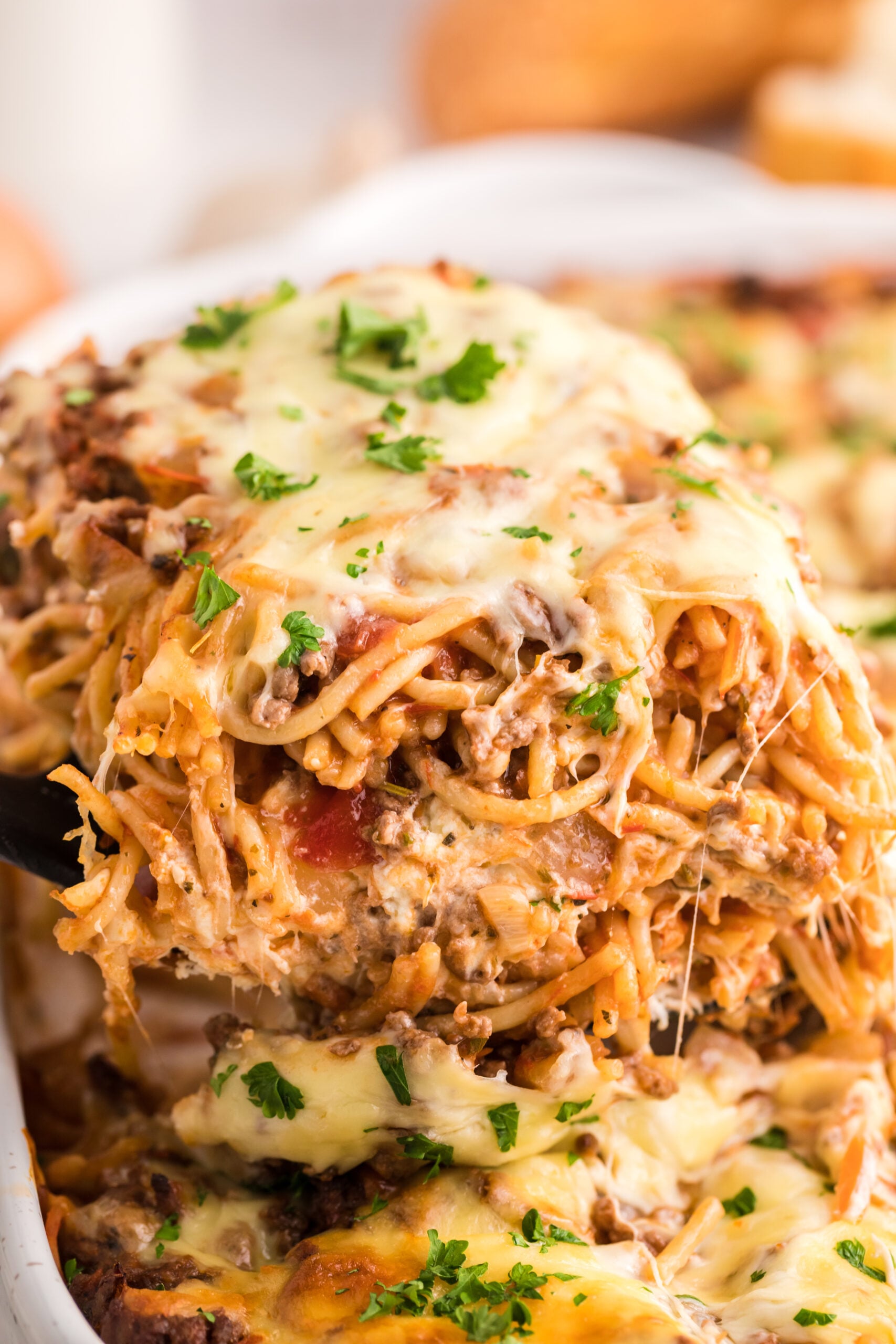 Million Dollar Spaghetti Casserole in a pan with a spatula lifting up a slice