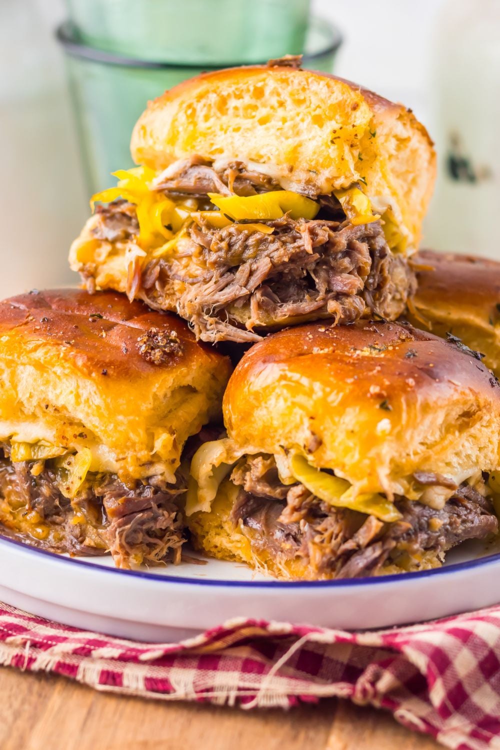 close up of Slow Cooker Mississippi Pot Roast Sliders on a plate with a red checkered towel under it 