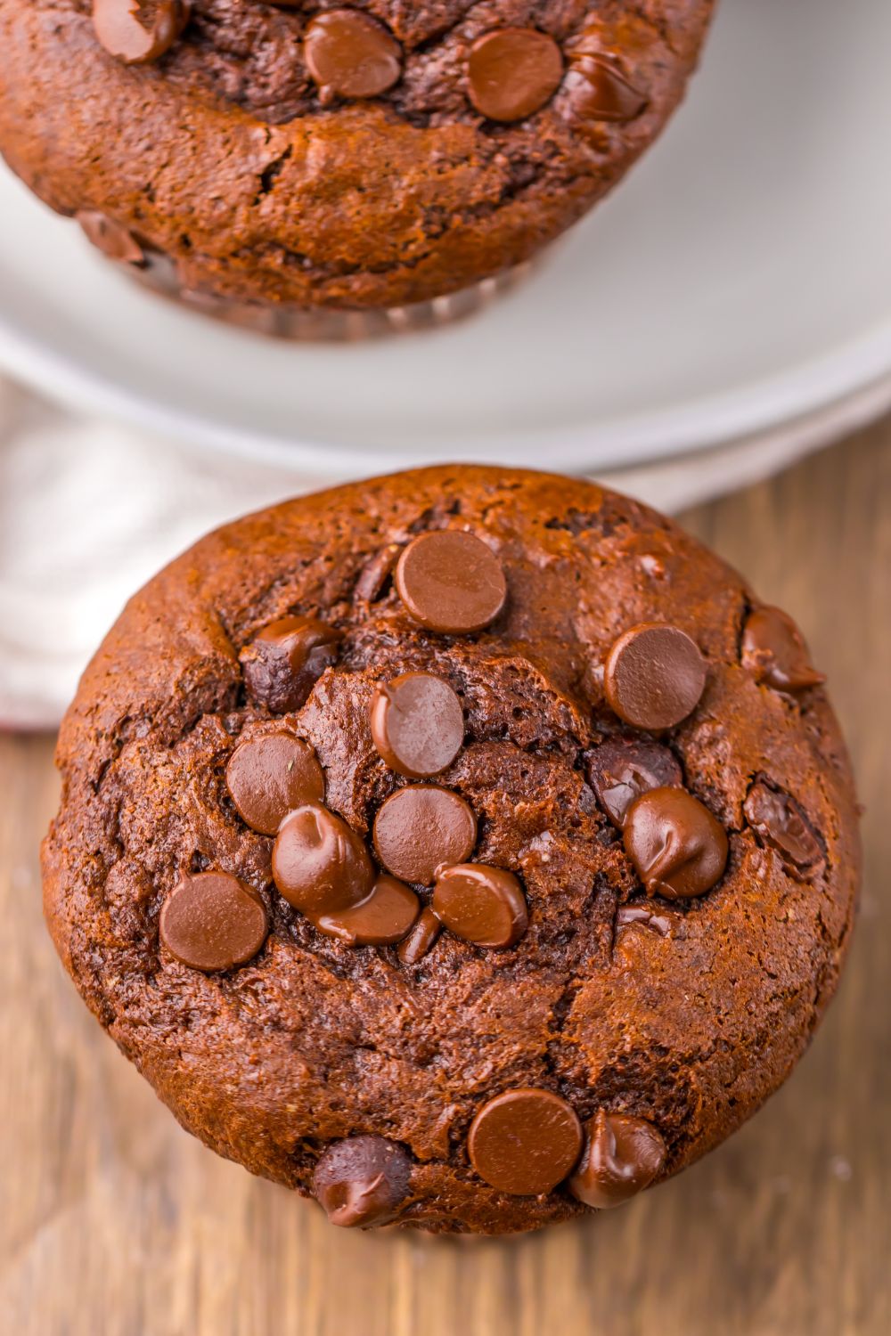 close up look of homemade Costco Double Chocolate Muffins on table with more on a plate behind it
