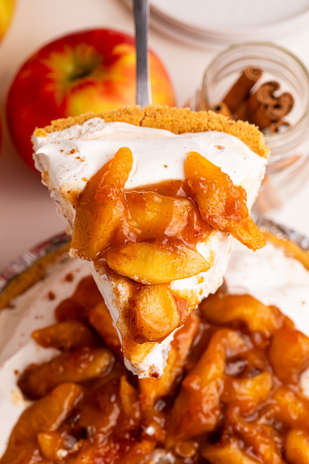 No Bake Apple Cheesecake pie on table with a slice coming out of pie plate