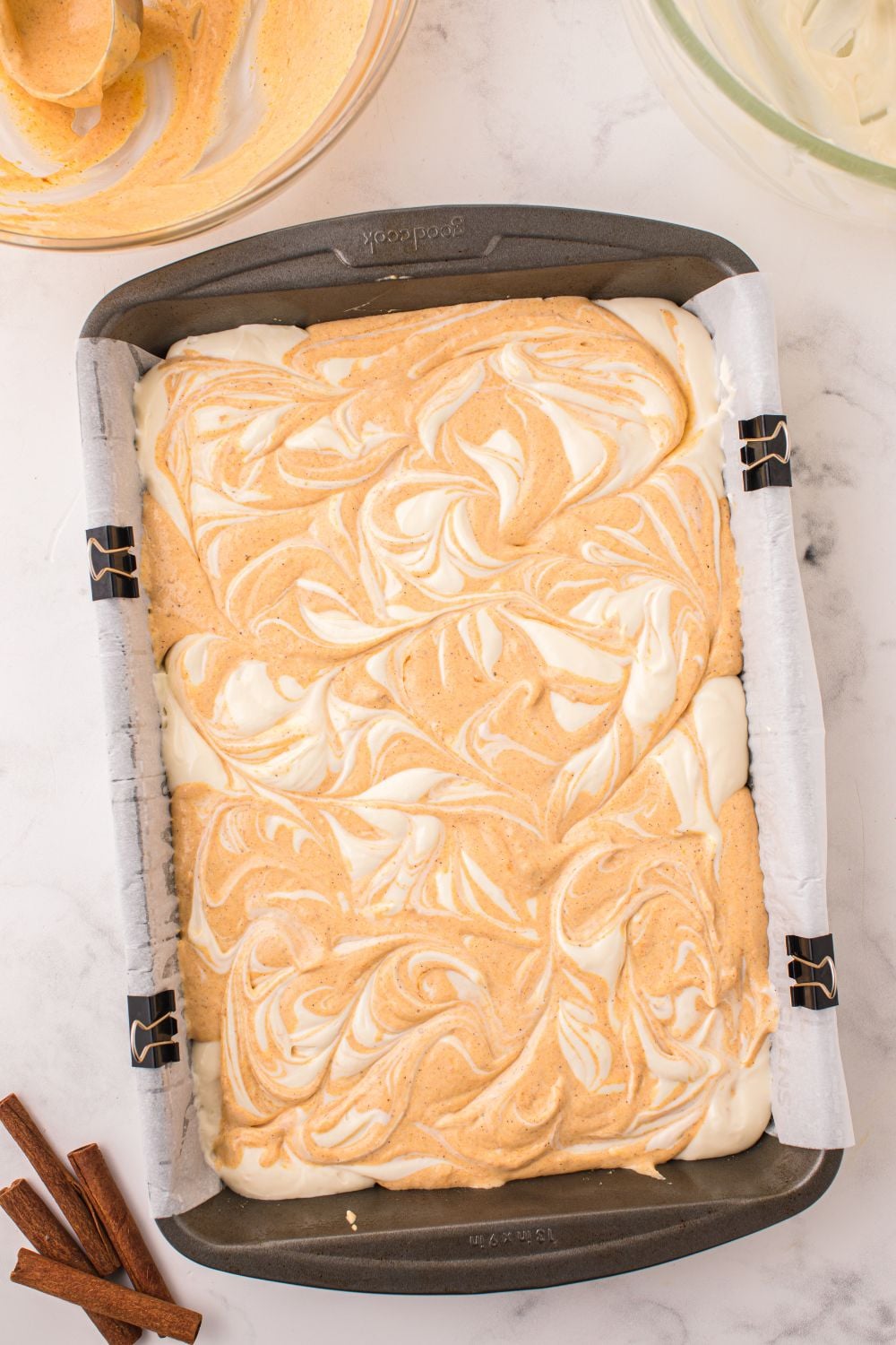 raw batter for Swirled Pumpkin Cheesecake Bars in pan on table