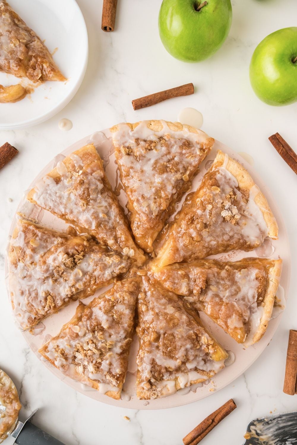 Apple Pie Pizza on table with cinnamon sticks and apples on table