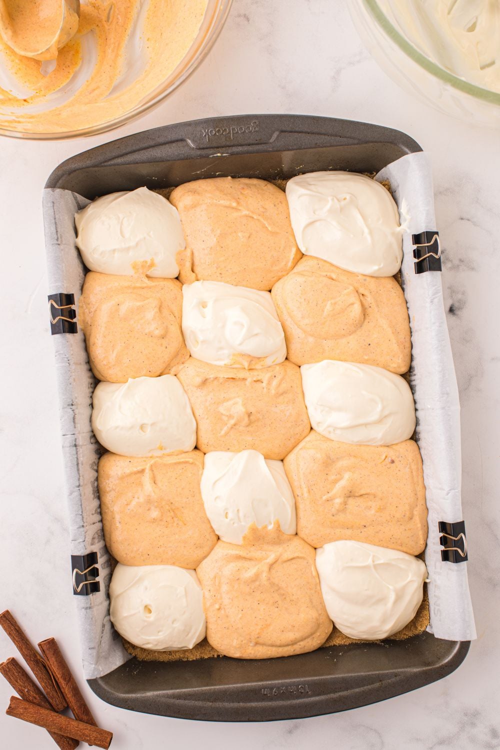 dollops of cheesecake bars on table for Swirled Pumpkin Cheesecake Bars in a pan