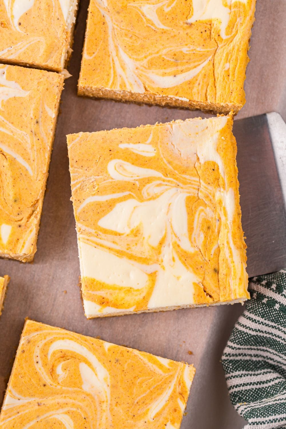 sliced Swirled Pumpkin Cheesecake Bars on table with a spatula under one