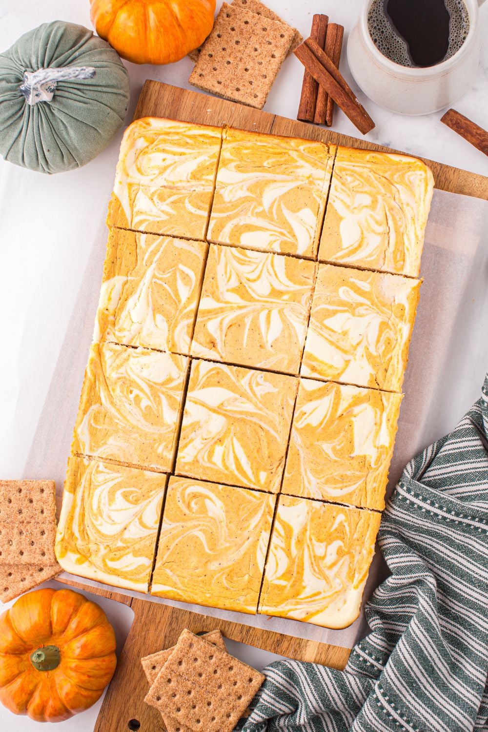 Swirled Pumpkin Cheesecake Bars sliced and placed on table with mini cheesecakes to side