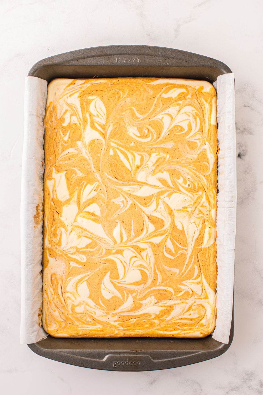 overhead look of baked Swirled Pumpkin Cheesecake Bars in pan on table